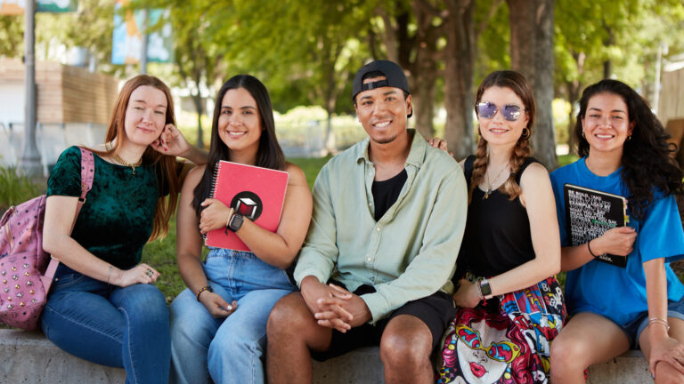 Five international students sitting outdoors smiling