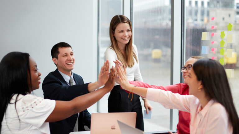 five business students giving a happy high five to one another