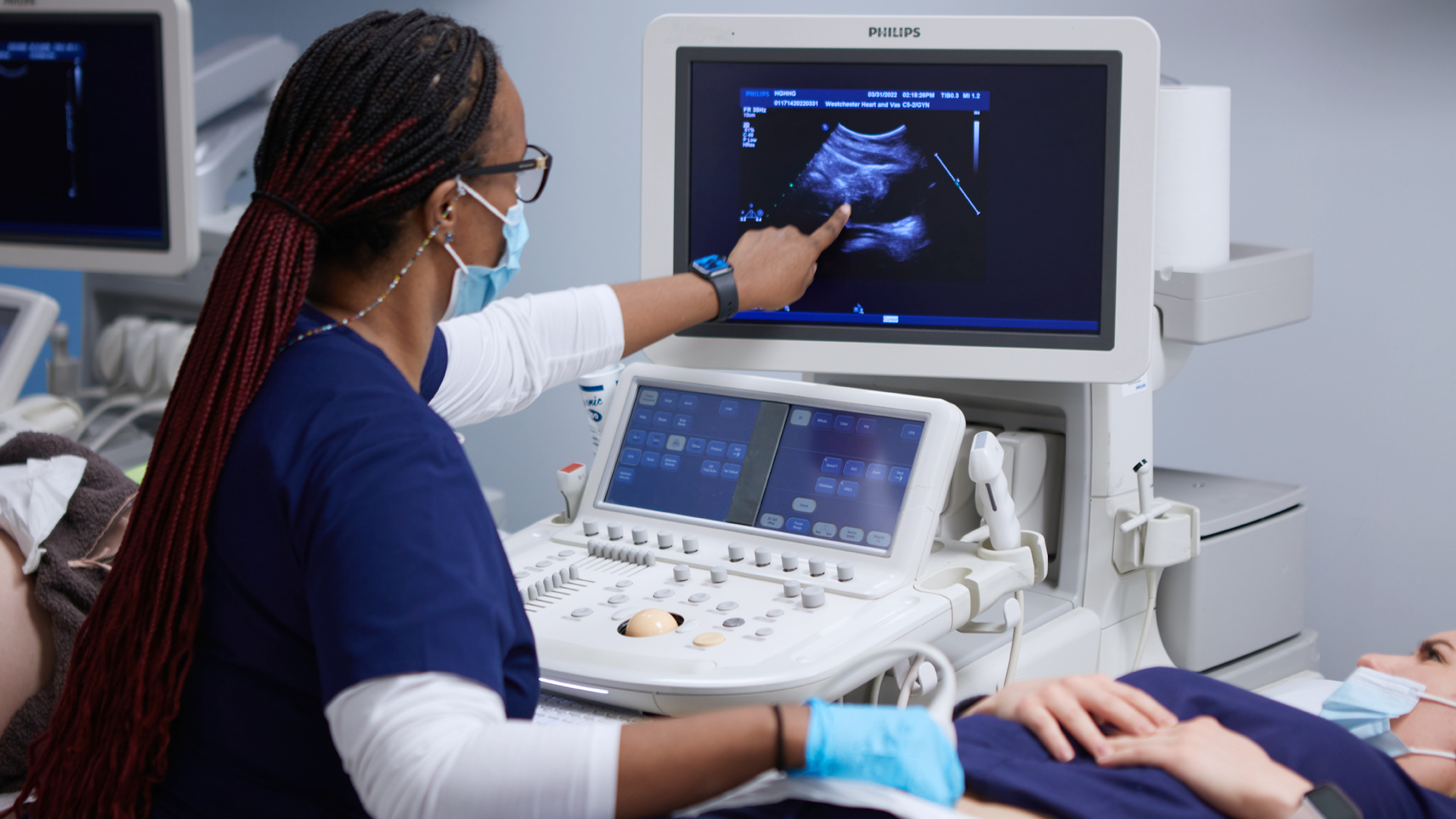 sonography student pointing out details of sonography scan on the screen