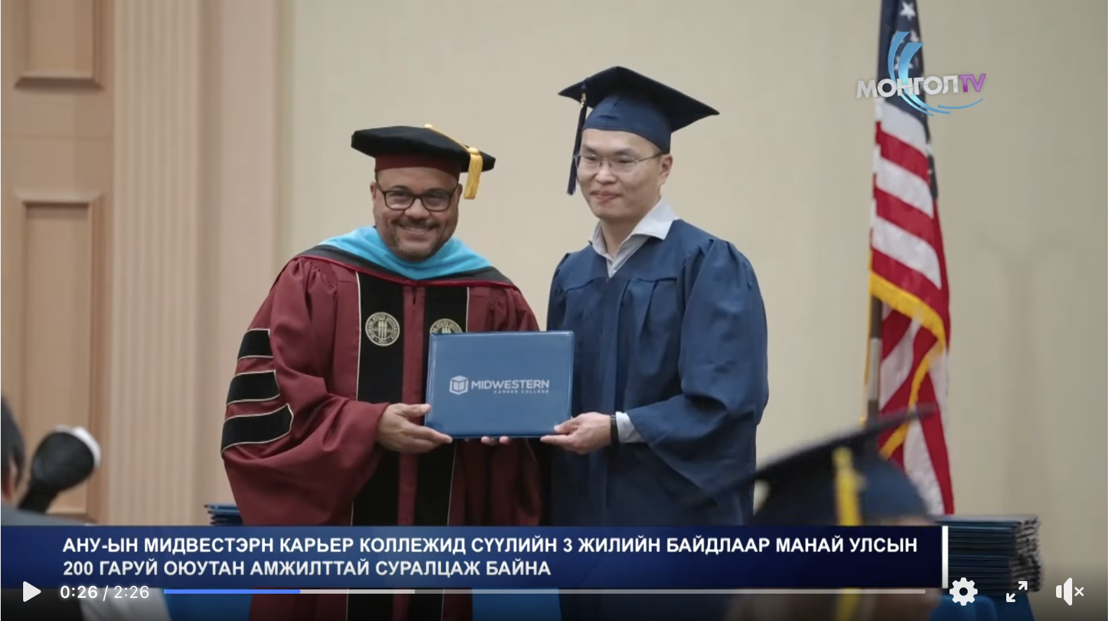 Screen clip from Mongol TV feature on MCC Graduation 2025 showing Dr. Angel Resto handing diploma to graduate.